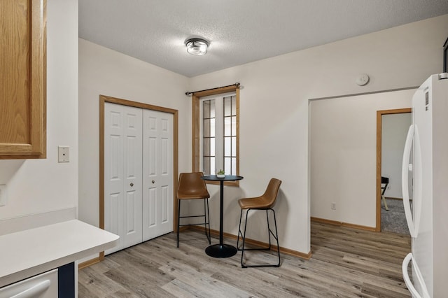 sitting room featuring light wood finished floors, a textured ceiling, and baseboards