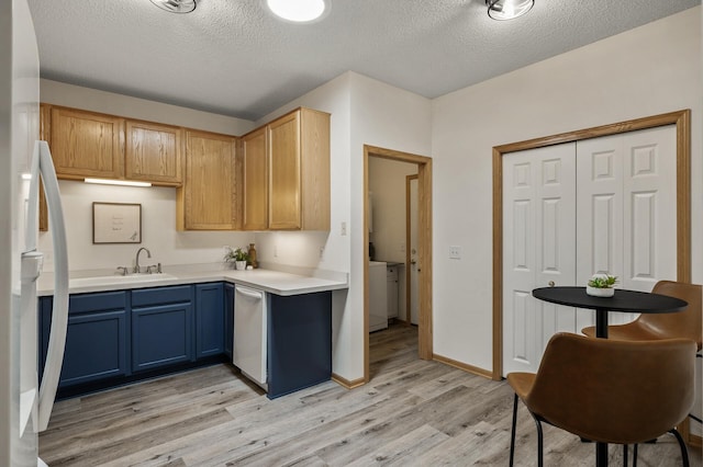 kitchen with light wood-style flooring, freestanding refrigerator, dishwasher, a textured ceiling, and light countertops