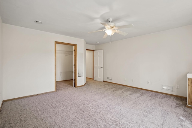 unfurnished bedroom featuring carpet, baseboards, and a walk in closet
