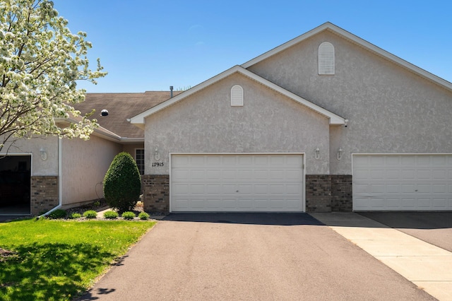 single story home with brick siding, stucco siding, and asphalt driveway