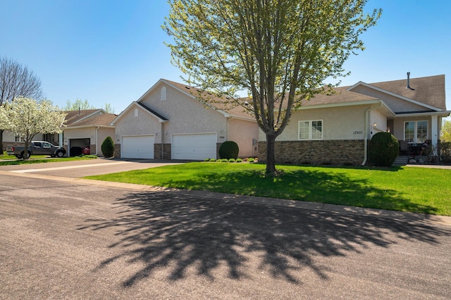 ranch-style house with a garage, concrete driveway, stucco siding, a front yard, and brick siding