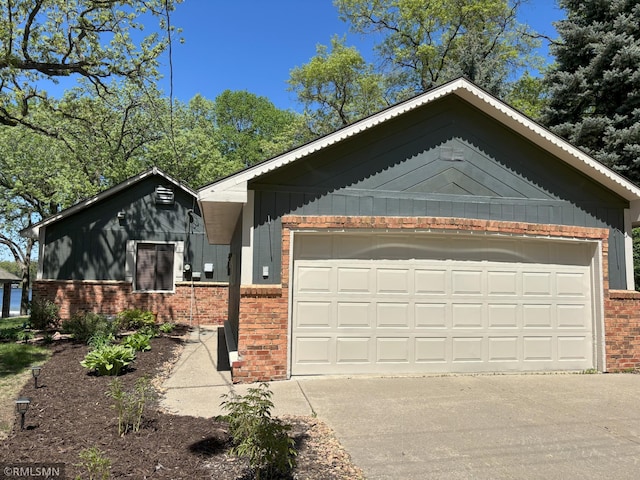 view of side of home with brick siding, board and batten siding, concrete driveway, and a garage
