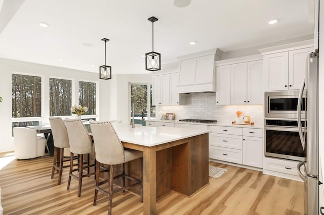 15359 Quamba St NE, Ham Lake, MN 55304 - kitchen with appliances with stainless steel finishes, custom range hood, light wood finished floors, backsplash, and white cabinets