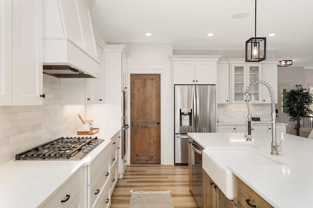 15359 Quamba St NE, Ham Lake, MN 55304 - kitchen with appliances with stainless steel finishes, a sink, custom range hood, decorative backsplash, and light wood-style flooring