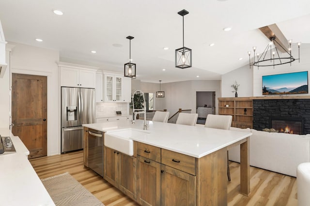 15359 Quamba St NE, Ham Lake, MN 55304 - kitchen with stainless steel appliances, open floor plan, light wood finished floors, a sink, and white cabinets