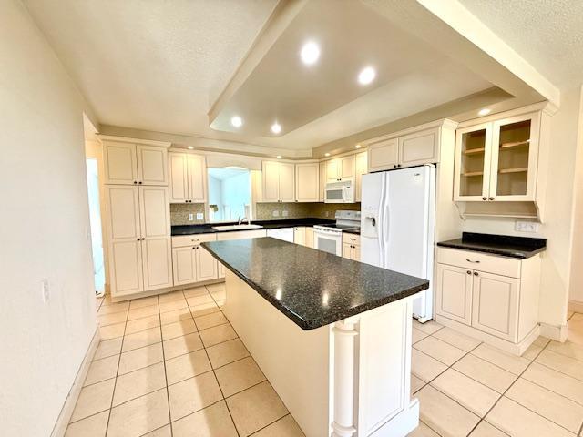 421 Main St E, Eitzen, MN 55931 - kitchen featuring white appliances, light tile patterned floors, baseboards, a sink, and a center island