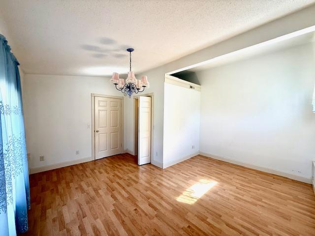 421 Main St E, Eitzen, MN 55931 - unfurnished dining area featuring light wood-type flooring, a chandelier, baseboards, and a textured ceiling