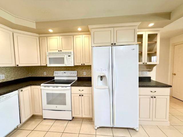 421 Main St E, Eitzen, MN 55931 - kitchen with white appliances, light tile patterned flooring, recessed lighting, glass insert cabinets, and dark countertops