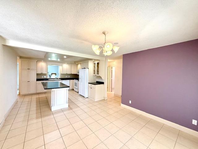 421 Main St E, Eitzen, MN 55931 - kitchen featuring white appliances, a textured ceiling, dark countertops, a chandelier, and a center island