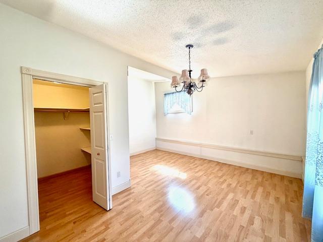 421 Main St E, Eitzen, MN 55931 - unfurnished dining area with wood finished floors, a chandelier, a textured ceiling, and baseboards