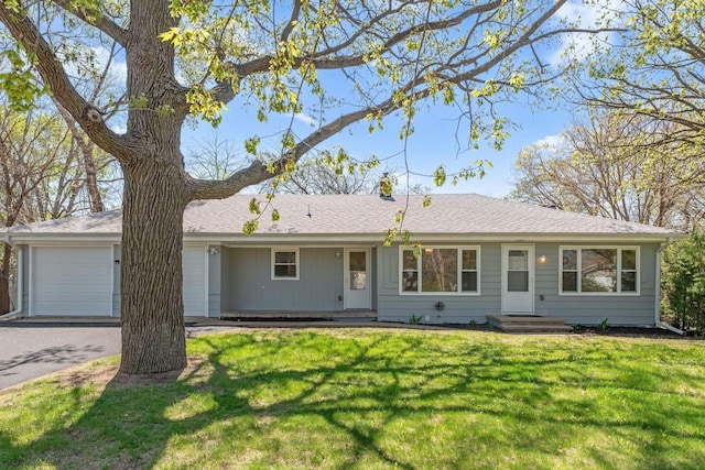 ranch-style house with an attached garage, a front yard, and asphalt driveway