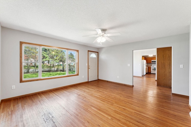 unfurnished living room with light wood-type flooring, a ceiling fan, baseboards, and a textured ceiling