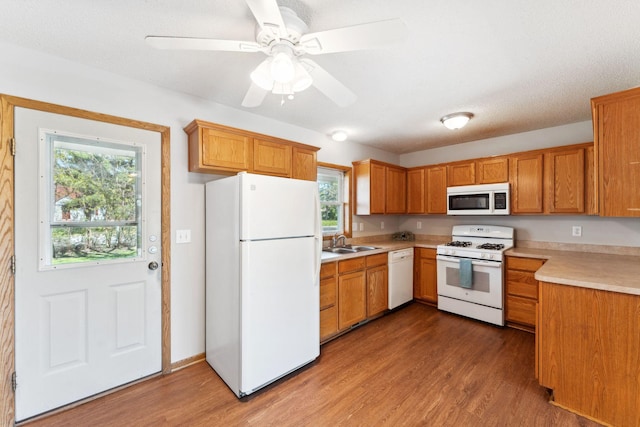 kitchen with white appliances, wood finished floors, light countertops, and a sink