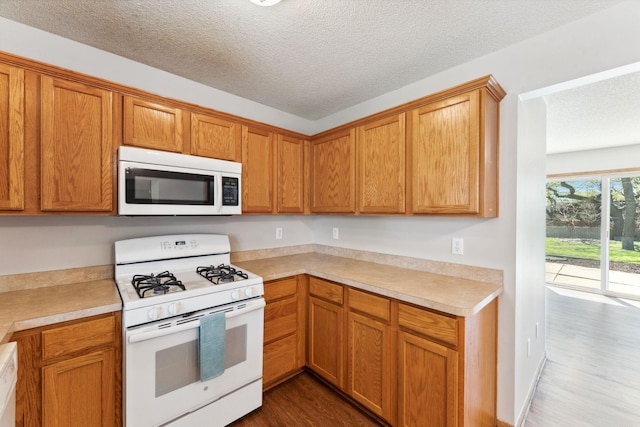 kitchen with white appliances, a textured ceiling, dark wood-style floors, light countertops, and brown cabinetry