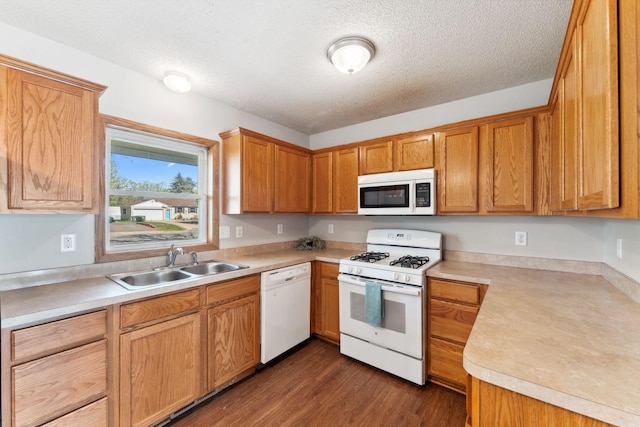 kitchen with white appliances, a sink, light countertops, a textured ceiling, and dark wood-style flooring