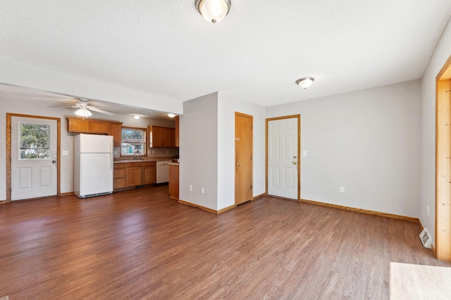 unfurnished living room with dark wood-style floors, baseboards, a ceiling fan, and a sink
