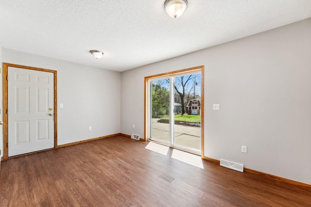 unfurnished room with wood finished floors, baseboards, and a textured ceiling