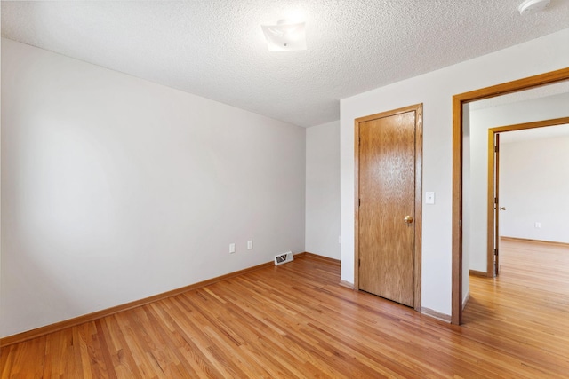 unfurnished bedroom with light wood finished floors, baseboards, and a textured ceiling