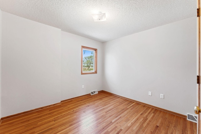 unfurnished room with light wood-style floors, baseboards, and a textured ceiling