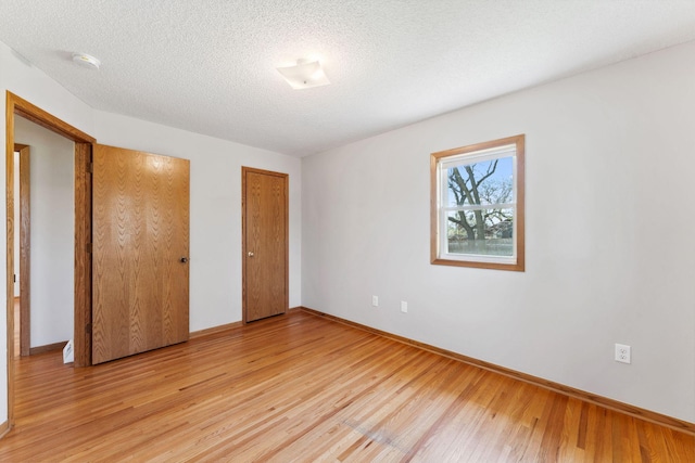 unfurnished bedroom with light wood-style flooring, baseboards, and a textured ceiling
