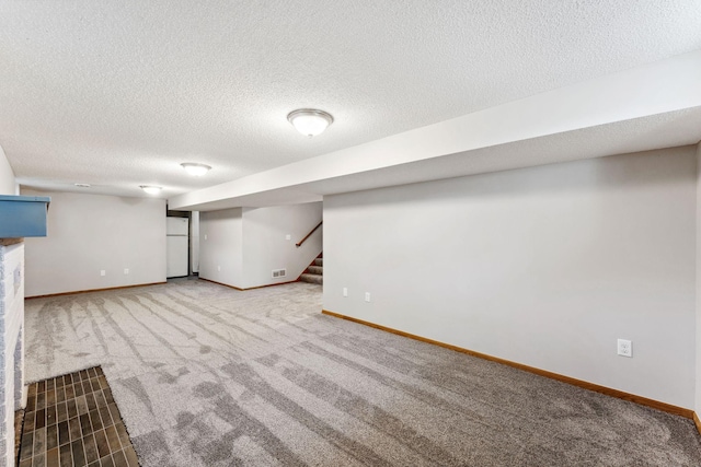 finished basement featuring carpet floors, baseboards, stairway, and a textured ceiling