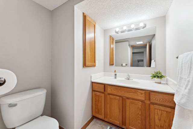bathroom with toilet, a textured ceiling, vanity, and baseboards