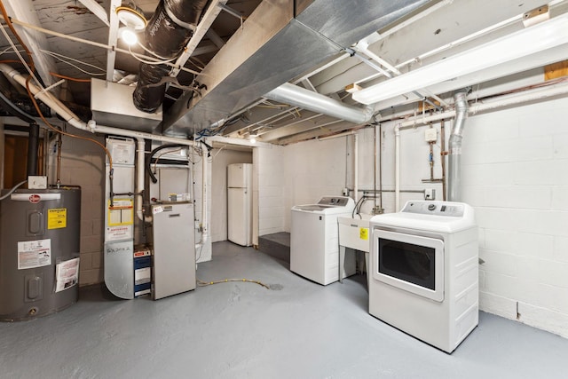 unfinished basement featuring electric water heater, washer and dryer, freestanding refrigerator, concrete block wall, and heating unit