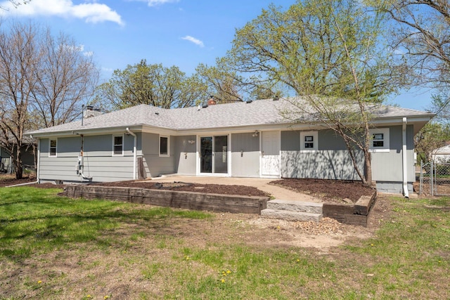 rear view of property with a chimney, a yard, a patio area, and a shingled roof
