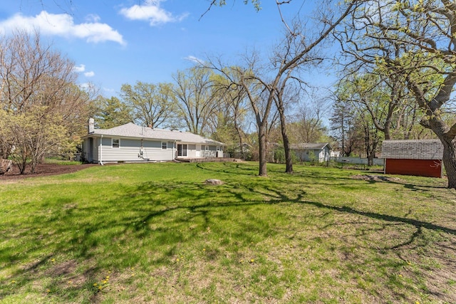 view of green lawn featuring an outbuilding and a storage unit