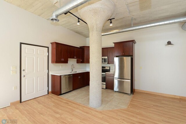 kitchen with stainless steel appliances, track lighting, light wood finished floors, and light countertops