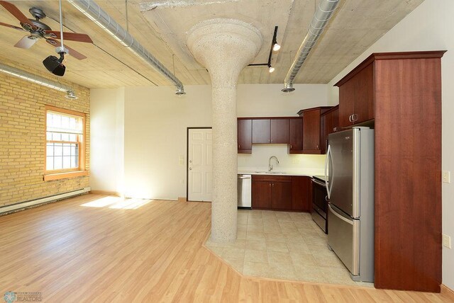 kitchen featuring stainless steel appliances, brick wall, a sink, a ceiling fan, and light countertops