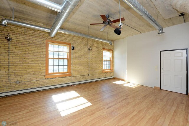 spare room with brick wall, a ceiling fan, plenty of natural light, and wood finished floors