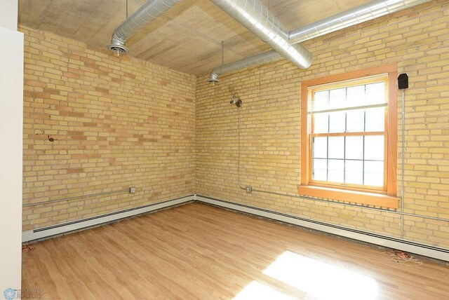 empty room featuring brick wall and wood finished floors