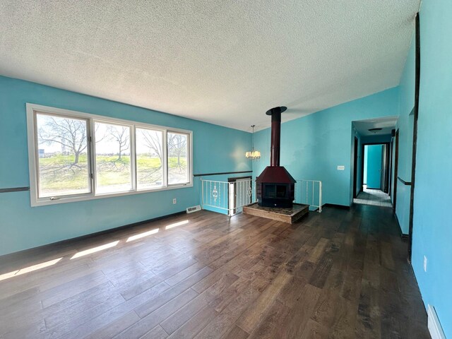4806 Monroe St NE, Columbia Heights, MN 55421 - unfurnished living room featuring dark wood-style floors, a wood stove, and a textured ceiling