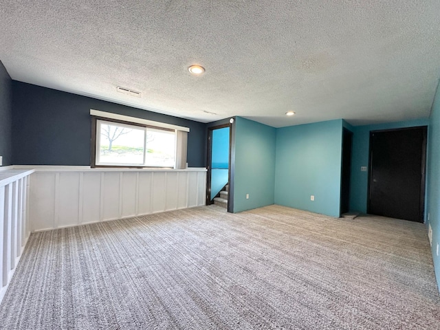 4806 Monroe St NE, Columbia Heights, MN 55421 - carpeted spare room with a textured ceiling, a wainscoted wall, a decorative wall, and stairs