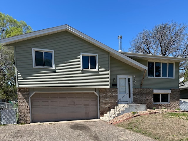 4806 Monroe St NE, Columbia Heights, MN 55421 - split foyer home featuring brick siding, an attached garage, and asphalt driveway