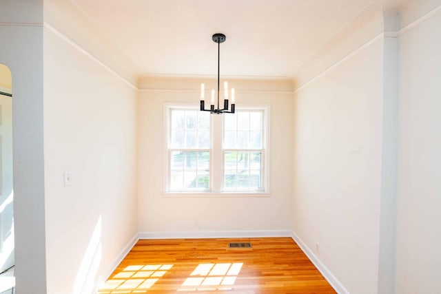 unfurnished dining area featuring a chandelier, light wood-type flooring, and baseboards