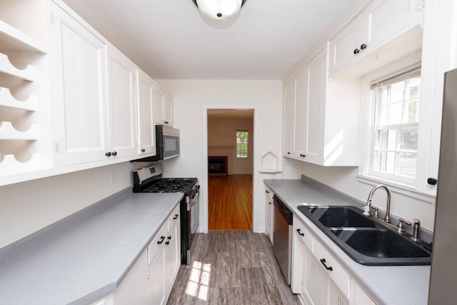 kitchen featuring appliances with stainless steel finishes, a sink, open shelves, and white cabinets