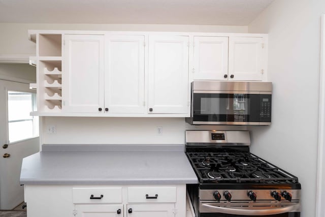 kitchen featuring appliances with stainless steel finishes, open shelves, white cabinetry, and light countertops