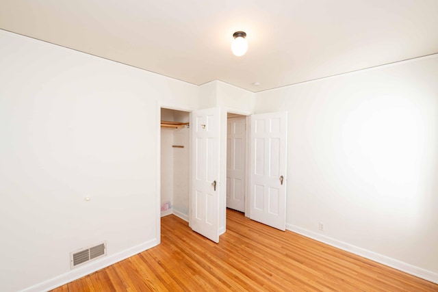 unfurnished bedroom with baseboards, light wood finished floors, and a closet