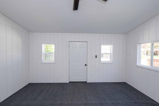 spare room featuring dark colored carpet and wooden walls