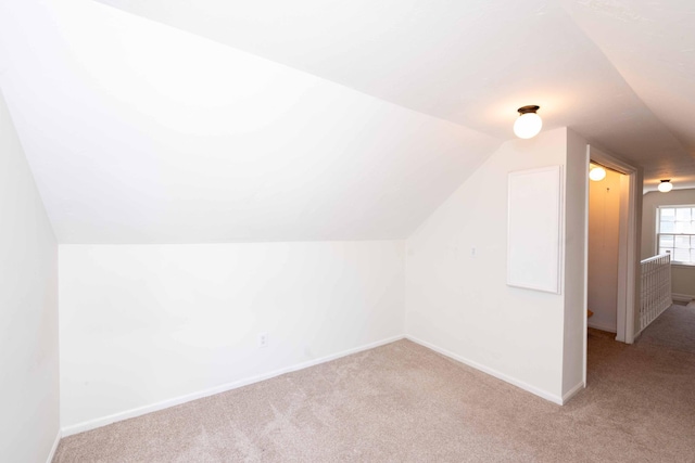additional living space featuring carpet flooring, lofted ceiling, and baseboards