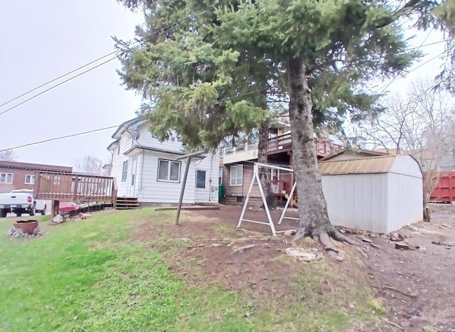 back of house featuring a storage shed, a deck, an outdoor structure, and a lawn