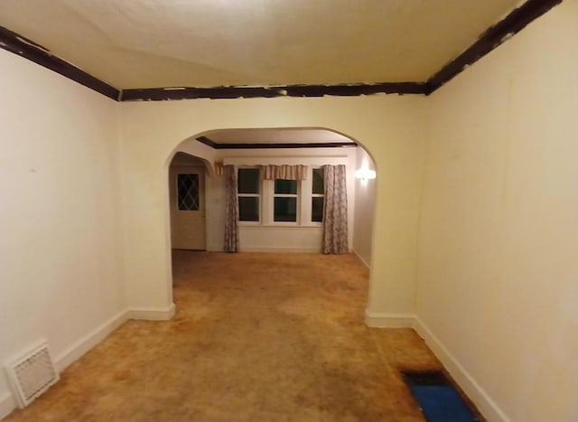 hall featuring arched walkways, crown molding, carpet flooring, and baseboards
