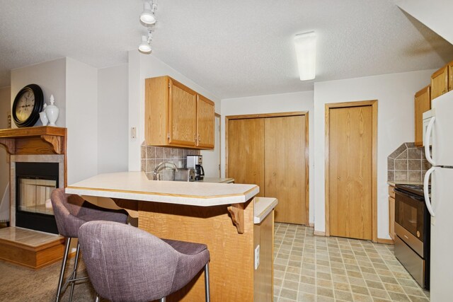 13210 Meadowood Trl NW Unit 63Nw, Coon Rapids, MN 55448 - kitchen featuring electric range, a breakfast bar area, a peninsula, decorative backsplash, and a fireplace