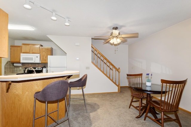 13210 Meadowood Trl NW Unit 63Nw, Coon Rapids, MN 55448 - kitchen featuring white appliances, a kitchen breakfast bar, light carpet, ceiling fan, and backsplash