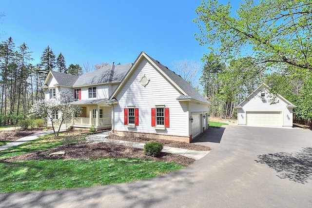 traditional-style home featuring a detached garage, covered porch, and an outbuilding