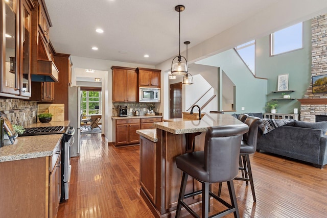 11200 Walnut Ln, Woodbury, MN 55129 - kitchen with appliances with stainless steel finishes, open floor plan, brown cabinetry, glass insert cabinets, and a kitchen bar