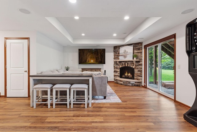 11200 Walnut Ln, Woodbury, MN 55129 - living area featuring a tray ceiling, wood finished floors, a stone fireplace, recessed lighting, and baseboards