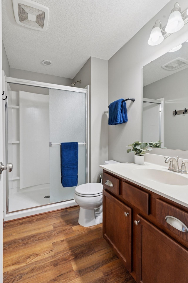 11200 Walnut Ln, Woodbury, MN 55129 - full bath featuring a stall shower, vanity, wood finished floors, toilet, and a textured ceiling